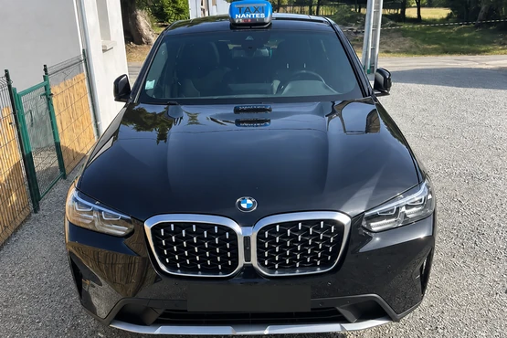 BMW sombre de face avec lumineux bleu Nantes, stationnée près d’une clôture.