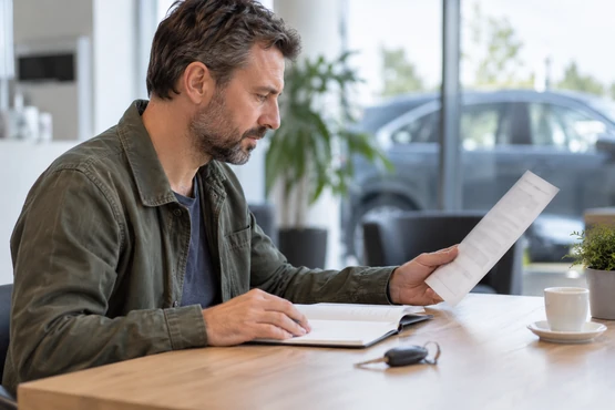 Une personne consulte des documents à une table près de clés de voiture