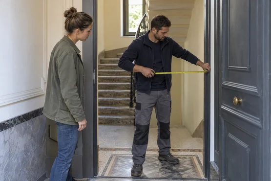 Deux personnes évaluant la largeur d’un passage dans un hall d’immeuble