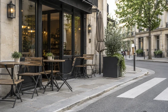 Une petite terrasse avec tables rondes, chaises en bois et entrée vitrée