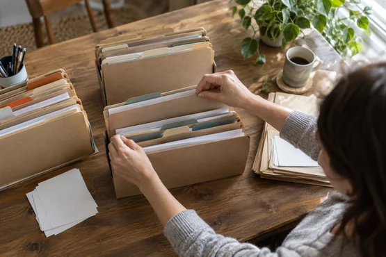 Mains triant des dossiers cartonnés et des fiches sur une table en bois