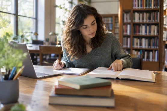 Lectrice comparant des notes avec un livre ouvert et un ordinateur