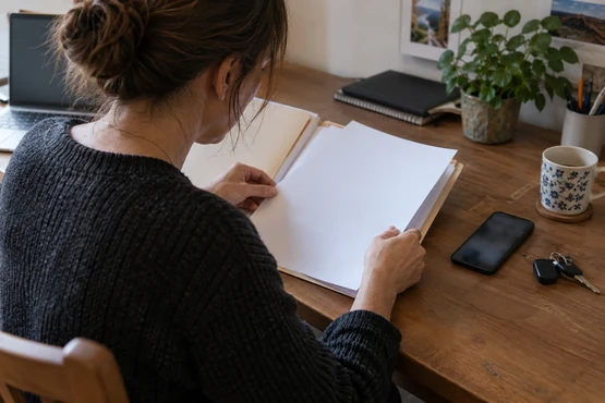 Un dossier papier, un téléphone et des clés de voiture sur un bureau domestique.