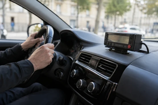 Un petit compteur de course est fixé dans un habitacle automobile éclairé par le jour.