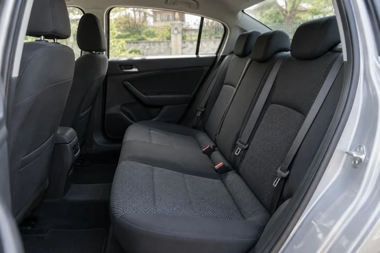 La banquette arrière sombre d’une voiture, avec appuie-têtes et ceintures visibles.