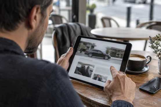 Une personne consulte une tablette affichant une page de transport volontairement floue.