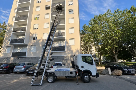 Camion monte-meuble blanc déployé devant un immeuble résidentiel à Lyon